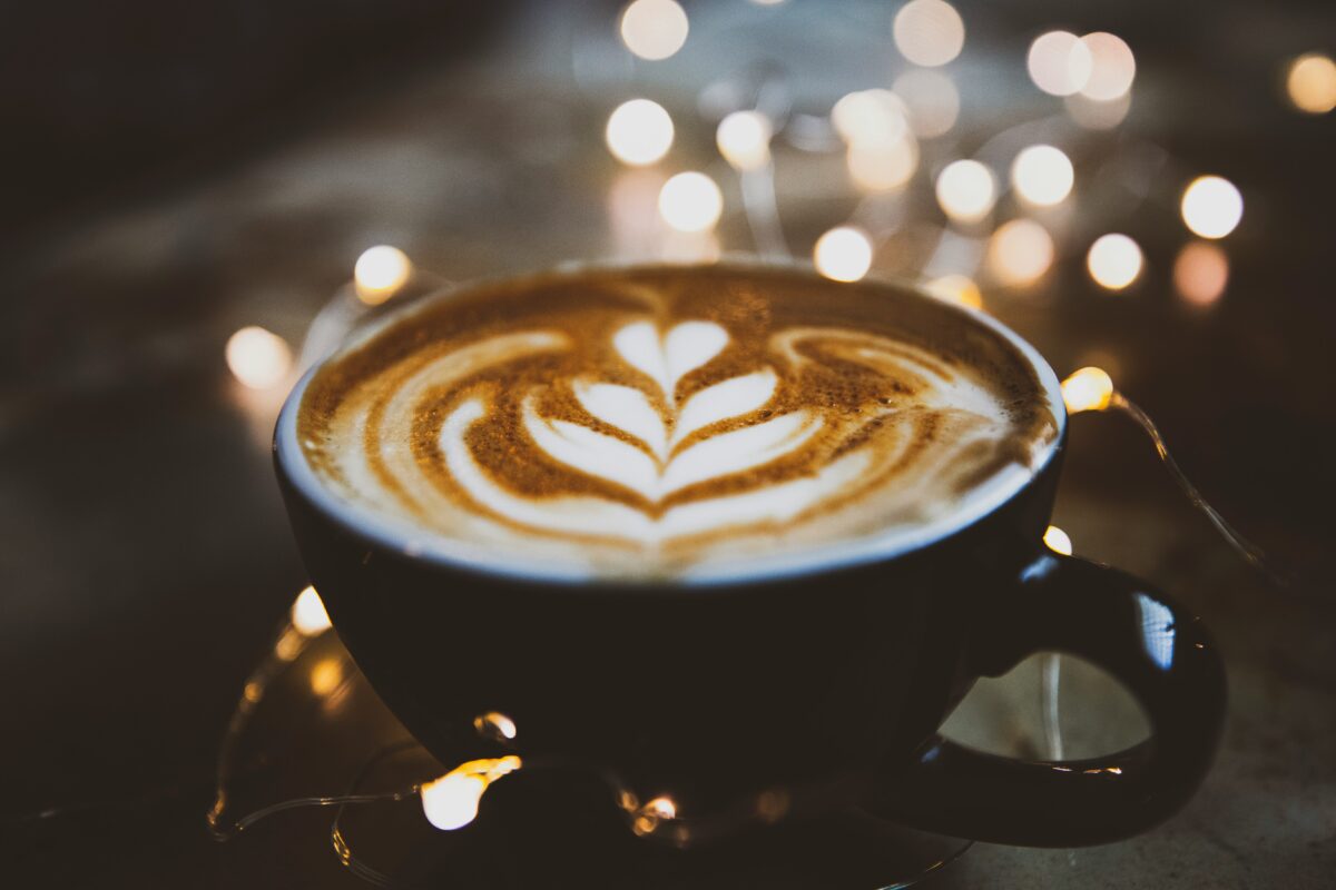 Latte Art: a cup of coffe is sitting on a table. The milk foam on top looks like a flower.